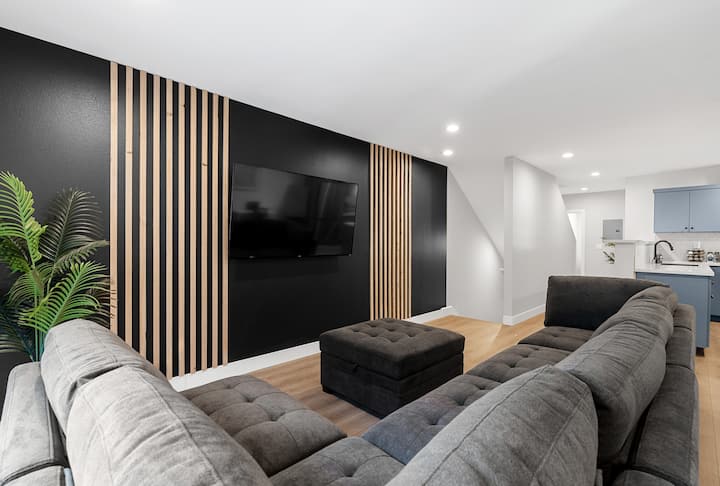 סלון מרווח עם שמיכה גדולה עם ספה חתוכה גדולה וטלוויזיה חכמה.