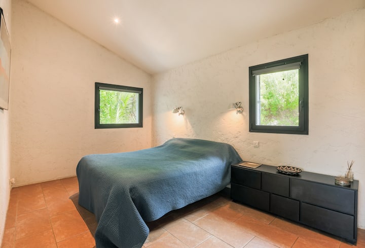 Chambre lumineuse avec lit double, grands rangements et vue verdoyante.