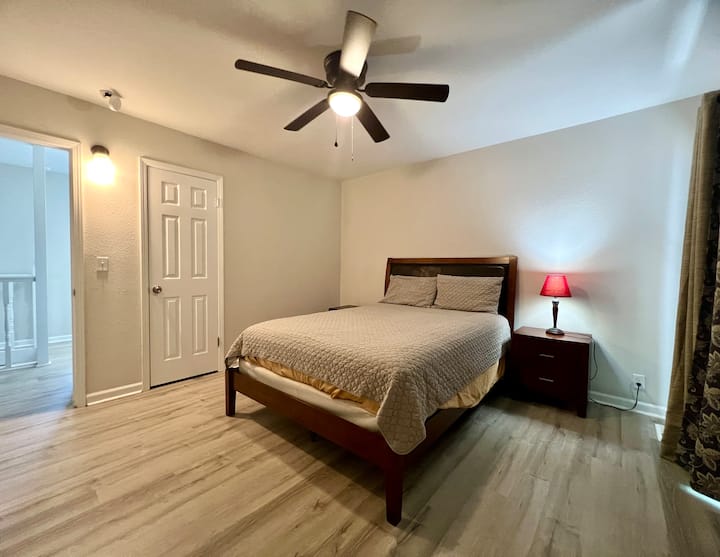 Este dormitorio sereno cuenta con una cama tamaño queen con cabecero acolchado, muebles de madera cálida y acceso privado al balcón. La iluminación suave y los tonos neutros crean un espacio tranquilo para descansar y relajarse.

