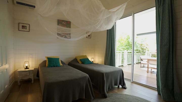 Светла стая с две единични легла, климатик, мрежа против комари и директен достъп до терасата. Тихо и просторно, с изглед към тропическата растителност. Собствена баня и тоалетна за допълнителен комфорт и уединение.