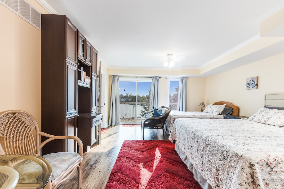 Amplio dormitorio principal con cómoda sala de estar, centro de entretenimiento integrado y acceso a balcón privado con vistas panorámicas.