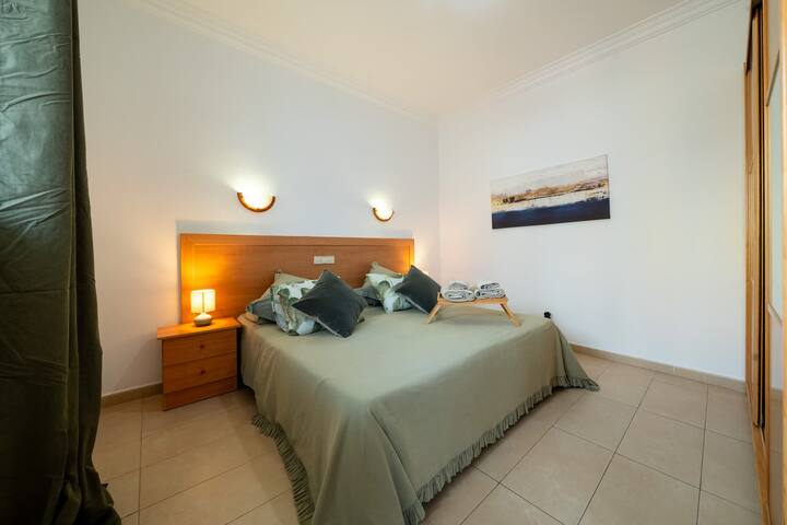 Chumba kikuu cha kulala chenye nafasi kubwa na angavu kilicho na kitanda cha watu wawili - mita 1.80, kabati kubwa na meza za kando ya kitanda. Imepambwa kwa rangi laini na maelezo ya kifahari, inatoa mazingira mazuri na yenye starehe, bora kwa ajili ya kupumzika baada ya kufurahia ufukwe au jiji