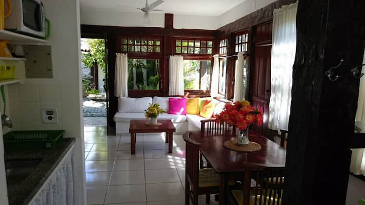 חדר אוכל עם שולחן וארבעה כיסאות ומטבח אמריקאי מאובזר לבישול ועם כלים לחמישה אנשים. 