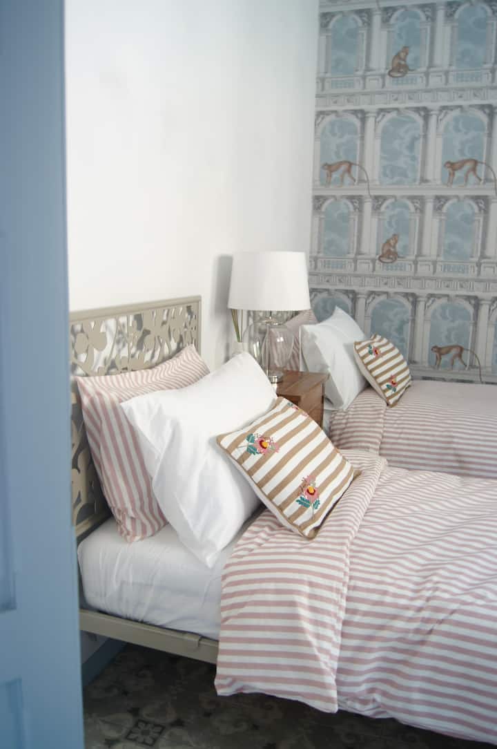 Chambre de plus de 15 mètres carrés avec papier peint Fornasetti et armoire design Lago (deux lits simples)