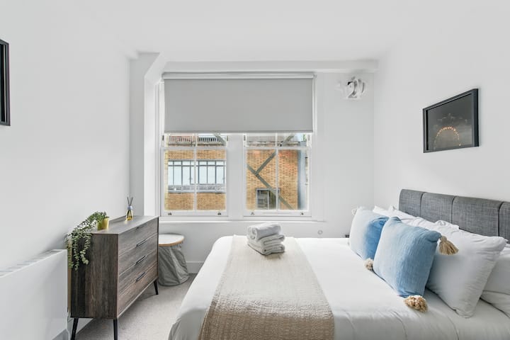 Chambre élégante avec des accents bleu doux, de la lumière naturelle et un lit confortable pour une nuit reposante.