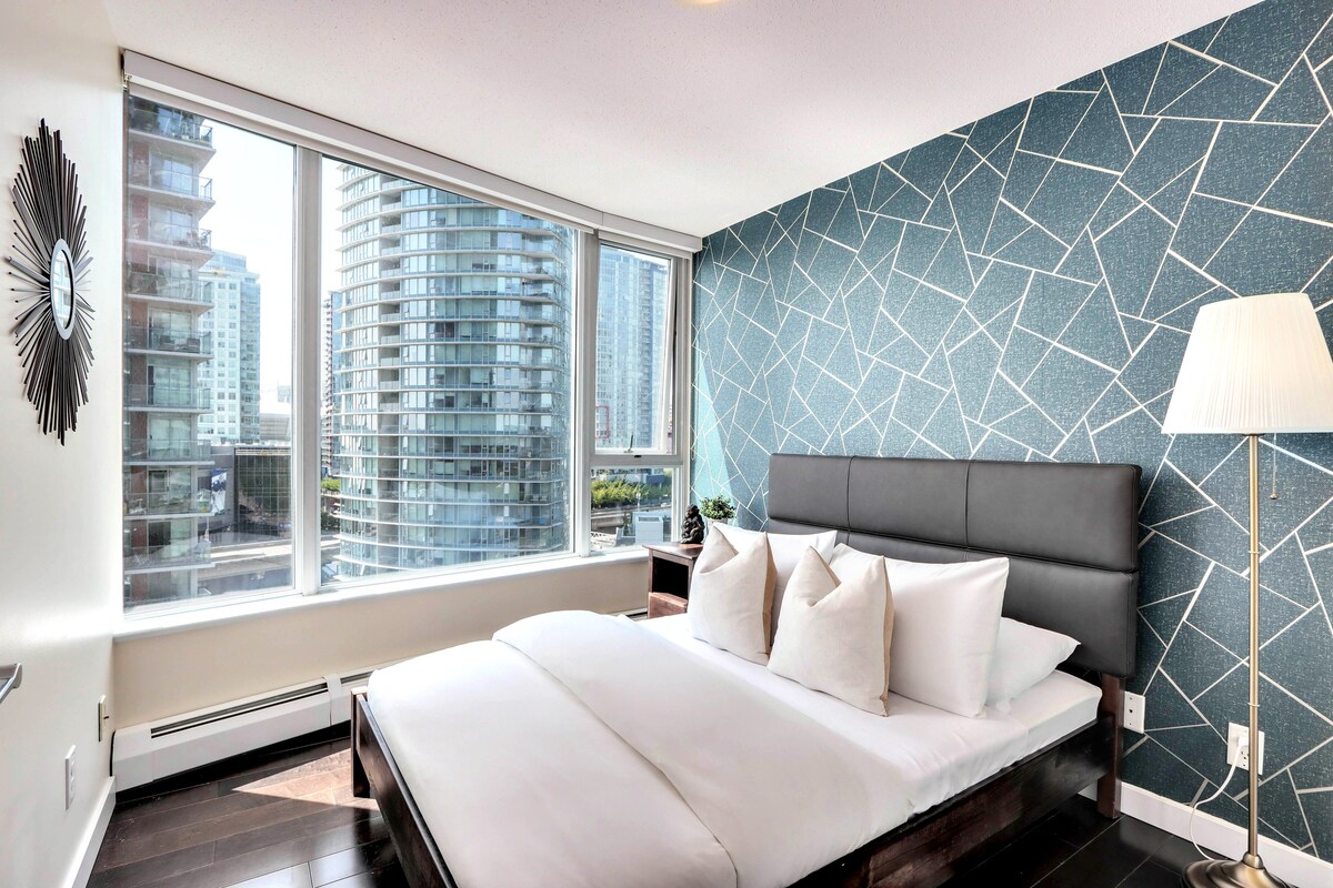 时尚的卧室配有豪华的标准双人床、时尚的几何装饰墙和落地窗，可欣赏迷人的城市景观。 完美融合了舒适和现代设计，让您在市中心享受宁静的夜晚！
