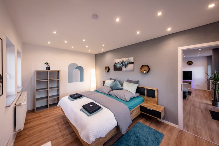 Модерна спална соба со топол шарм - постелнината со интегрирана ноќна масичка и индиректно осветлување ве покануваат да се опуштите пред да заспиете