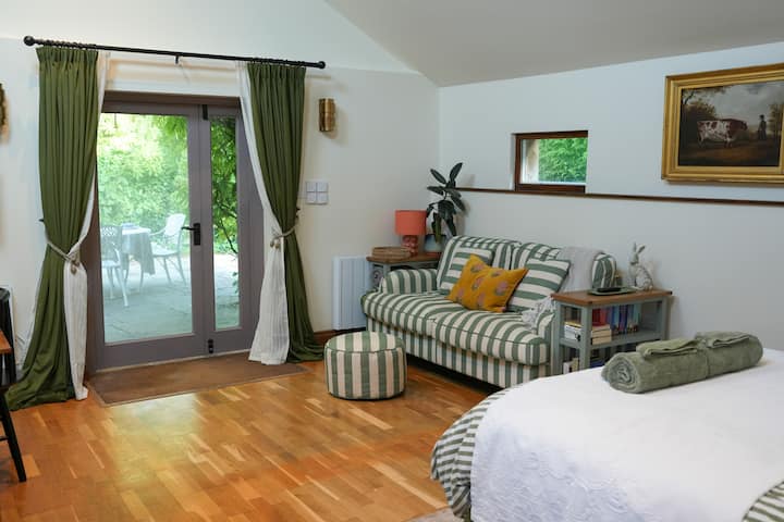 พื้นที่นั่งเล่นแบบเปิดโล่งพร้อมพื้นผิวที่อบอุ่นและแสงธรรมชาติ โซฟาต่อไปเป็นเตียงคู่