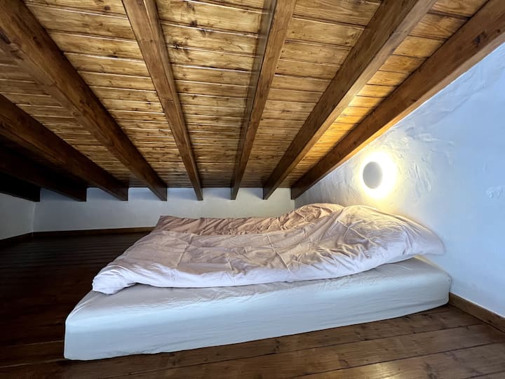 Krevat dopio "queen" në mezzanine, i arritshëm nëpërmjet shkallëve dhe me pamje të hapur nga hapësira e ndenjjes. 