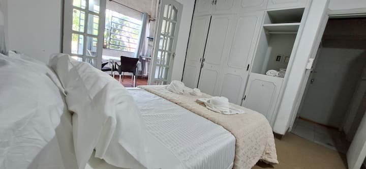 غرفة نوم مشرقة مع سرير مزدوج وخزانة كبيرة وإمكانية الوصول إلى شرفة تطل على الحديقة. مثالي للراحة والاستمتاع بالهدوء