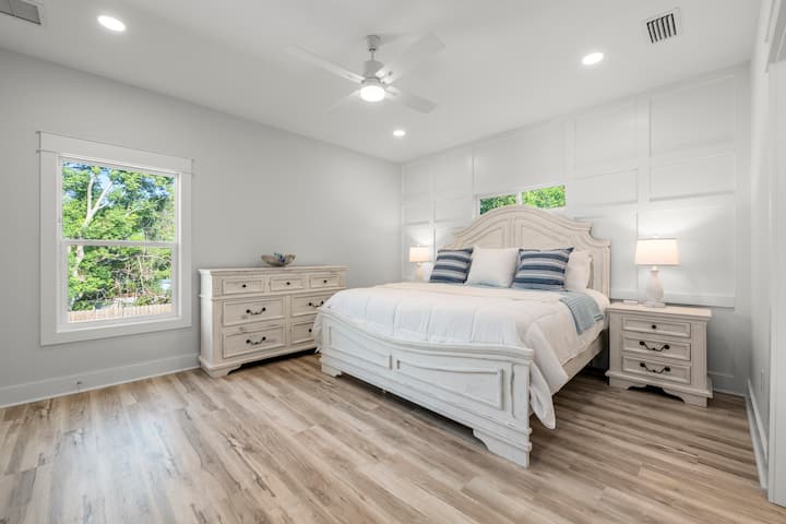 Suite amplia y luminosa con cama tamaño king, muebles blancos y detalles en azul suave. La luz del sol entra por grandes ventanales, creando un refugio sereno a pocos minutos de la playa, perfecto para mañanas lentas y noches de descanso después de un día en la arena.

