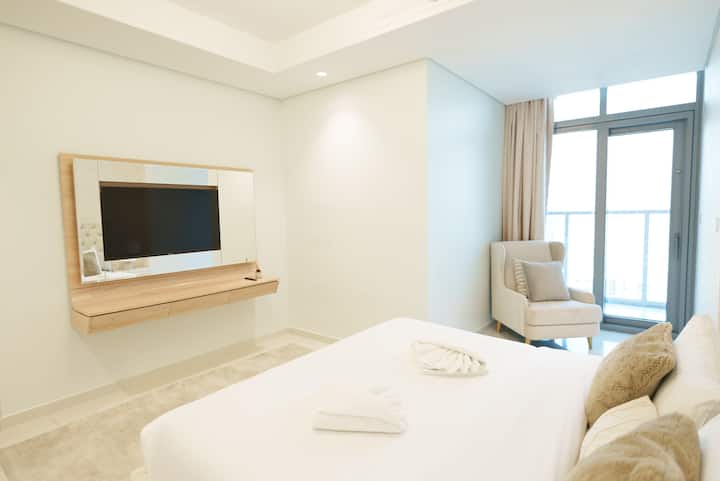 Спокојна главна спална соба со кадифена постелнина, паметен телевизор, удобно катче за седење и пристап до балконот дизајниран за максимална удобност и релаксација.