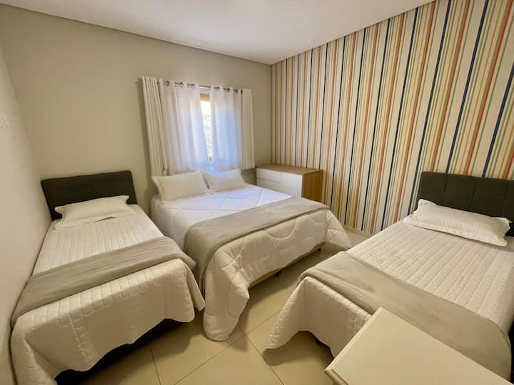 Dormitorio con una cama tamaño queen y dos camas individuales con ropa de cama.