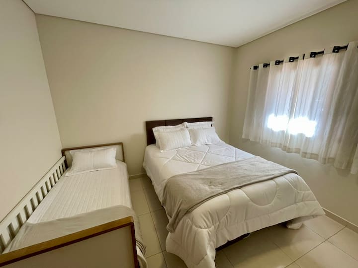 Dormitorio con cama de matrimonio y cama individual, todos con ropa de cama.