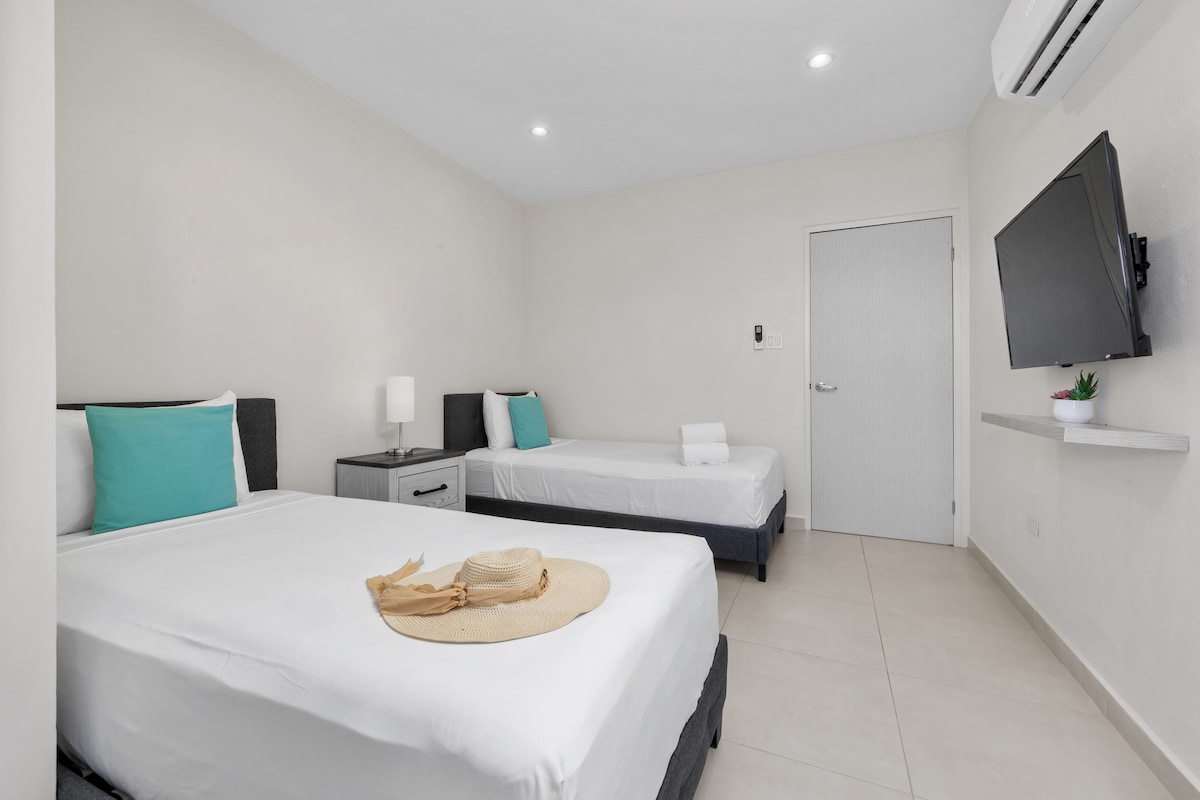 Კომფორტული ორადგილიანი კონფიგურაცია კონდიციონერით, კედელზე მიმაგრებული ბრტყელეკრანიანი ტელევიზორითა და თანამედროვე განათებით.