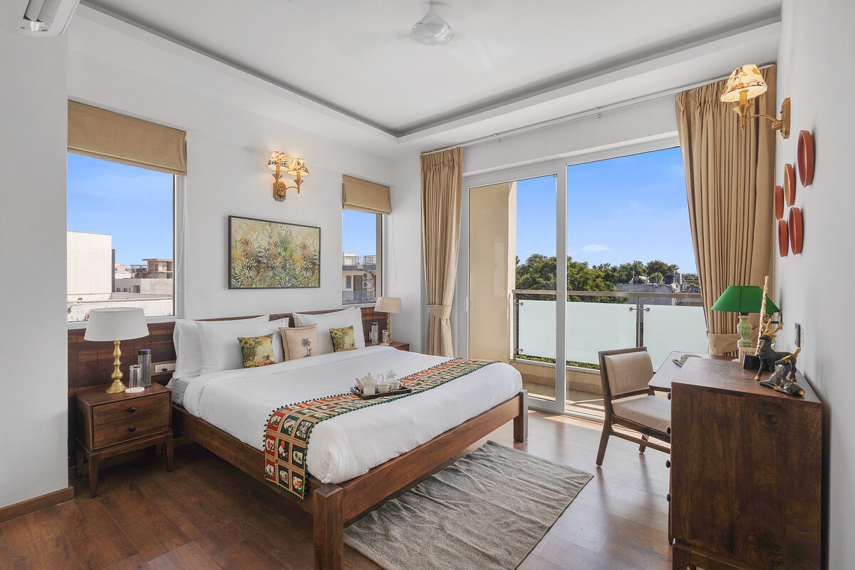 Cozy bedroom with a soft double bed, calming décor, and a private balcony — perfect for morning sunlight and fresh air.