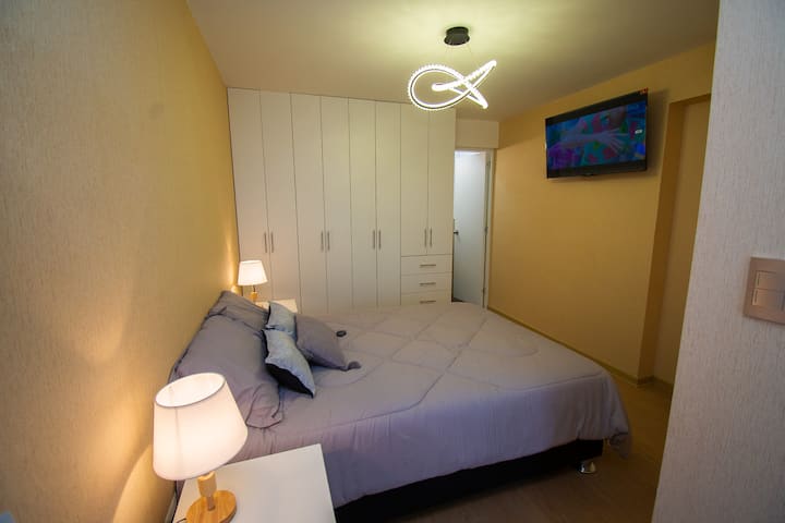 Priestranná hlavná izba s vlastným hygienickým vybavením a praktickým stolom, ideálny priestor na kombináciu odpočinku, pohodlia a funkčnosti.