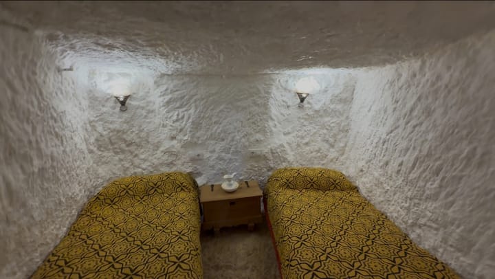 تحتوي غرفة النوم الكهفية الثانية على سريرين مفردين، وهي مثالية للأصدقاء أو الأطفال الذين تزيد أعمارهم عن 10 سنوات. مع الجدران الحجرية الطبيعية والإضاءة الناعمة، فإنه يوفر مساحة مريحة وآمنة وفريدة حقًا للاستمتاع بسحر الإقامة داخل الجبل.