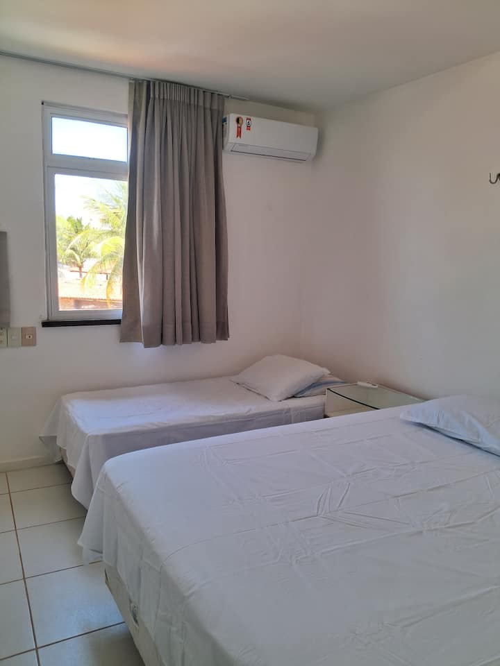 Chambre au premier étage avec un lit queen-size et un lit simple; climatisation, table de chevet et fenêtre avec rideau et occultant.
Crochets (supports) disponibles pour un hamac!
Toilettes accessibles et salle de bain sociale en face de la chambre.