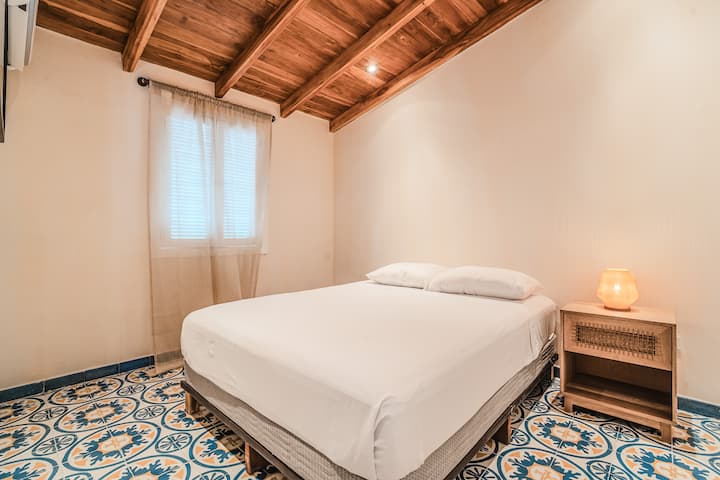 Топло, минималистичко одморалиште: брачен кревет (широк 150-179 см), изложен дрвен таван, хидрауличен под и мека ламба на ноќното шкафче. Проѕирни завеси кои ја пренесуваат светлината за мирен одмор.