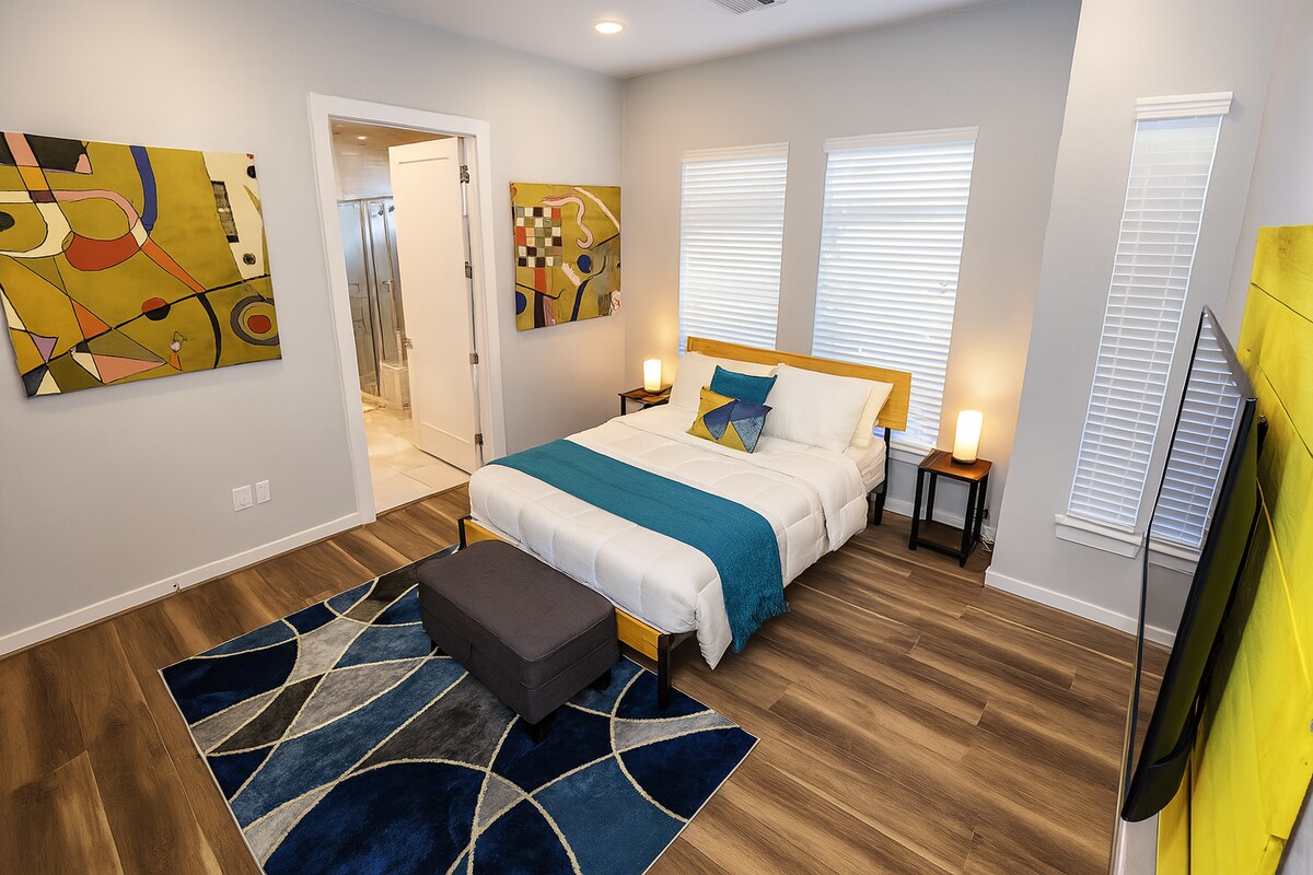 Ontspan in deze serene mastersuite met pluche wit beddengoed, blauwgroene accenten en een 55" tv tegen een gloeiende decoratieve achtergrond. Natuurlijk licht, moderne kunst en strakke afwerkingen creëren een boetiekhotel-sfeer met alledaags comfort