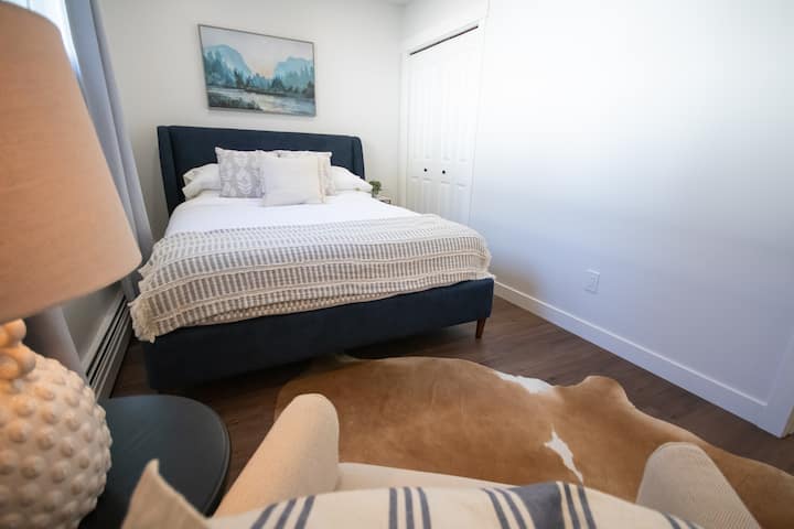 Svetlá spálňa s posteľou Queen v spodnej jednotke s čistou posteľnou bielizňou a umeleckými prvkami. Ideálna druhá spálňa pre rodiny alebo priateľov cestujúcich spolu, ktorá ponúka súkromie a pohodlie počas pobytov v Calgary.