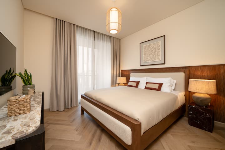 Елегантни спални соби со кадифена постелнина, модерен декор и изобилна природна светлина низ големи прозорци.