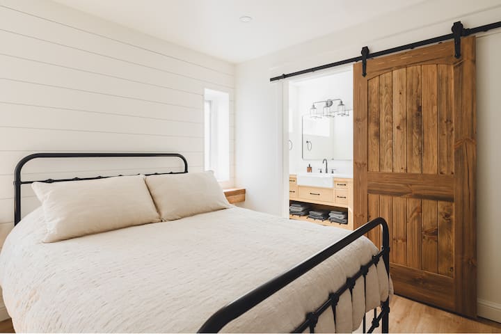 Bedroom #2- Main floor of the cottage featuring one queen bed with a ensuite stand up shower layout. 