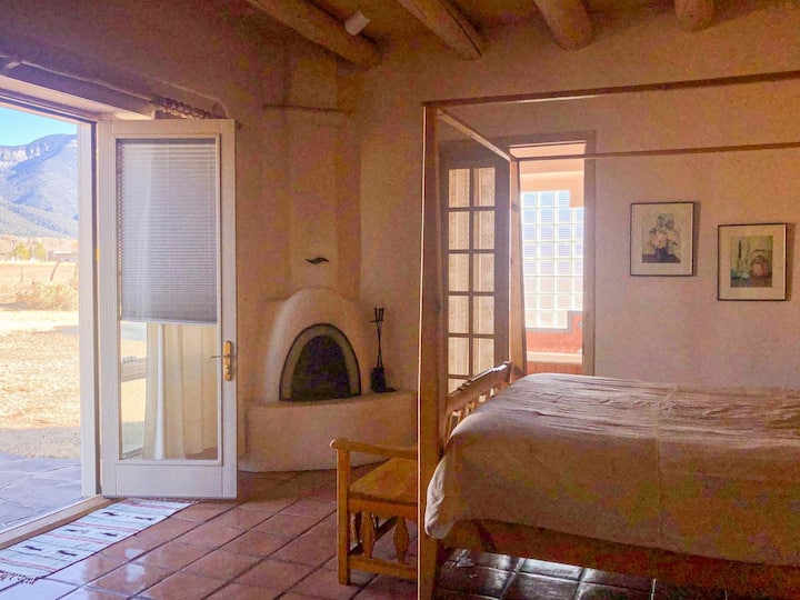 Chambre principale. 8 pieds de haut portes françaises avec vue sur la montagne.  Portes-fenêtres donnant sur la salle de bain principale. Cheminée à bois Kiva.  Armoire avec télévision connectée. Grand dressing. Banc en bois sculpté. Lit avec poteau en forme de crayon. Chauffage au sol radiant. Couvertures supplémentaires