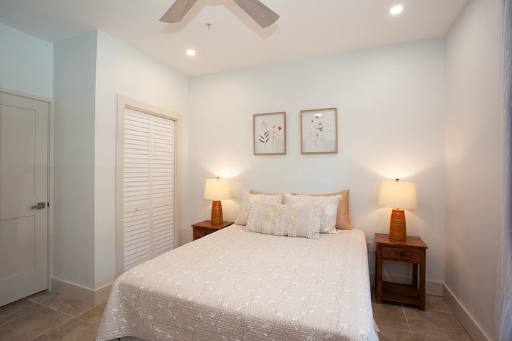 Cama tamaño queen en el acogedor dormitorio con paneles que oscurecen las ventanas de la habitación