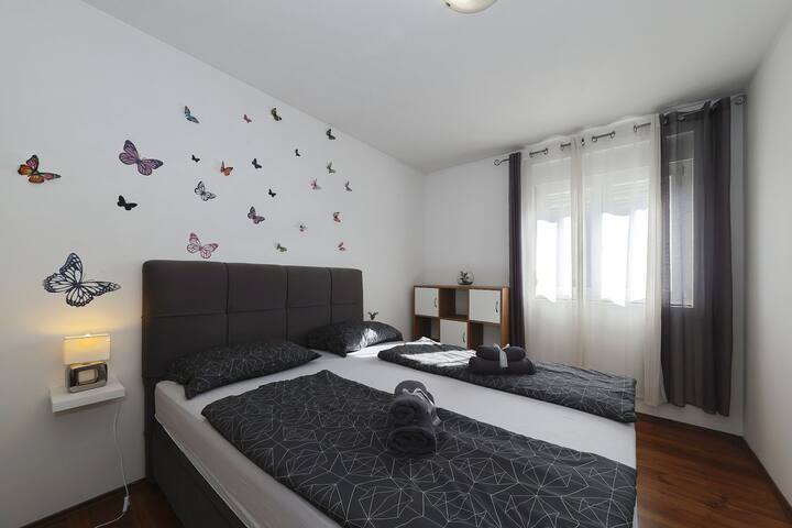 明亮舒适的卧室，配有标准双人床、柔软的床上用品和俏皮的蝴蝶墙面装饰。 迷人的空间，自然光线充足，非常适合安静入住。