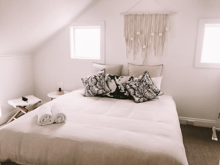 Relájate en el segundo dormitorio de arriba, completo con una cama tamaño king, baño abierto y un baño privado, diseñado para la comodidad y la relajación.