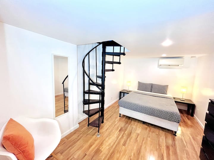 Schlafzimmer auf der unteren Etage mit einem geteilten, kanallosen Heiz- und Kühlsystem für optimalen Komfort. In der Ecke befindet sich ein gemütlicher Sessel, der einen perfekten Ort zum Entspannen schafft.