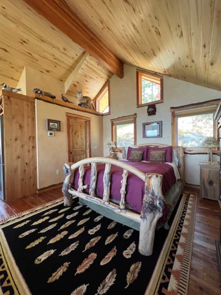 מיטת קווין סייז מעוצבת במונטנה, דלת לחדר הרחצה עם זאב ערבות מפוחלץ, פסיון, דביבון וברווזים מגולפים ביד של הבעלים המוצגים למעלה.