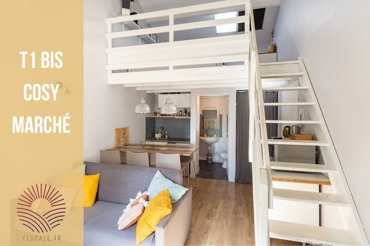 The cozy living area features a spacious sofa adorned with vibrant cushions, complemented by a dining table set for meals. A staircase leads to the mezzanine, while subtle lighting enhances the modern decor throughout the open space.