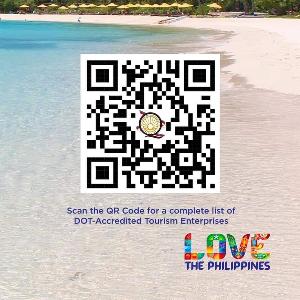 A serene beach scene captures the gentle shoreline meeting the clear blue water. A QR code is displayed prominently, inviting scanning for more information. The 'Love the Philippines' text in bright, colorful letters adds a vibrant touch to the image.
