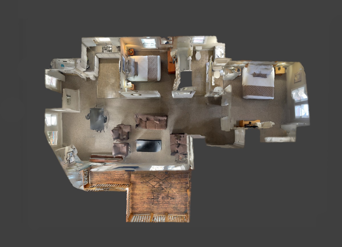 An aerial view of the penthouse apartment layout is displayed, showcasing a spacious living area with seating arranged around a central coffee table. Two bedrooms are visible, each featuring a bed and natural light from nearby windows. The overall design reflects an inviting and functional space.