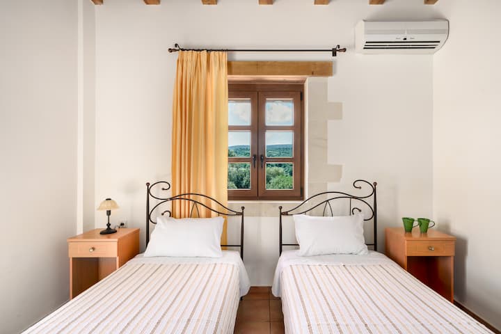 Um quarto bem iluminado e arejado com duas camas de solteiro, perfeito para hóspedes que viajam juntos