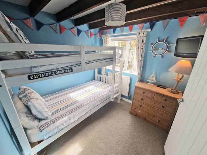Sleep tight in the nautical-themed bedroom with comfy bunk beds and a TV with DVD player—perfect for kids or guests seeking a cozy, fun stay.