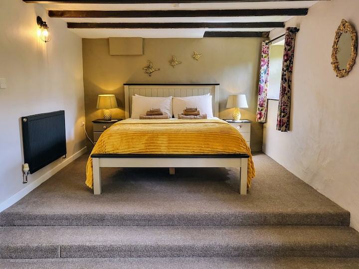 The downstairs double bedroom has split level floor, exposed beams, and an en-suite bathroom