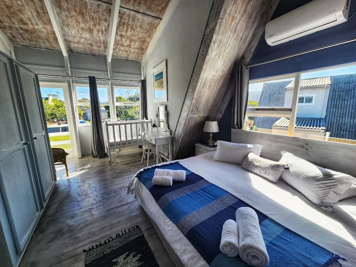 The main bedroom also features a cozy balcony overlooking the pool, perfect for keeping an eye on the kids while enjoying distant views of the Outeniqua Mountains.