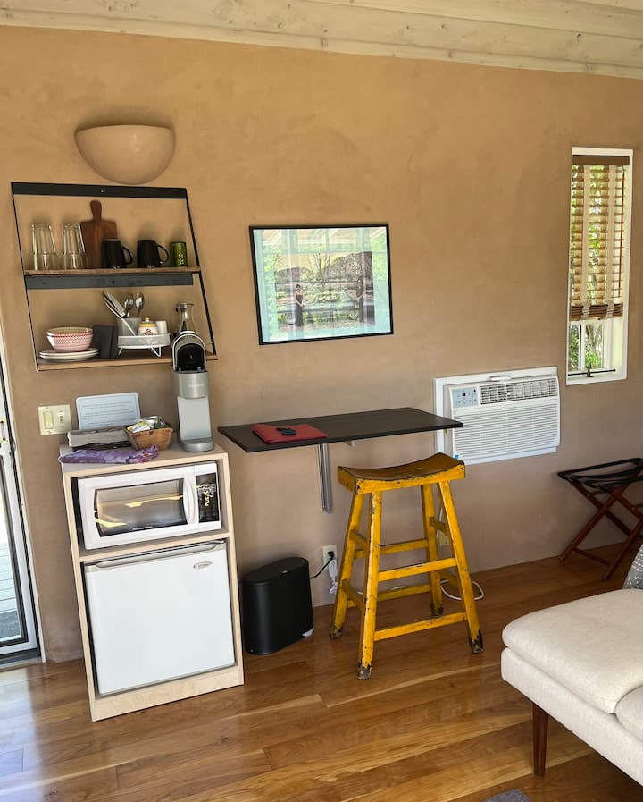 Queen size bed, with AC, a private bath with a small shower. There is a mini fridge, microwave, tea kettle for pour over coffee and tea -  not a full kitchen and is not suitable for making full meals. Intended for snacks and re-heating leftovers.