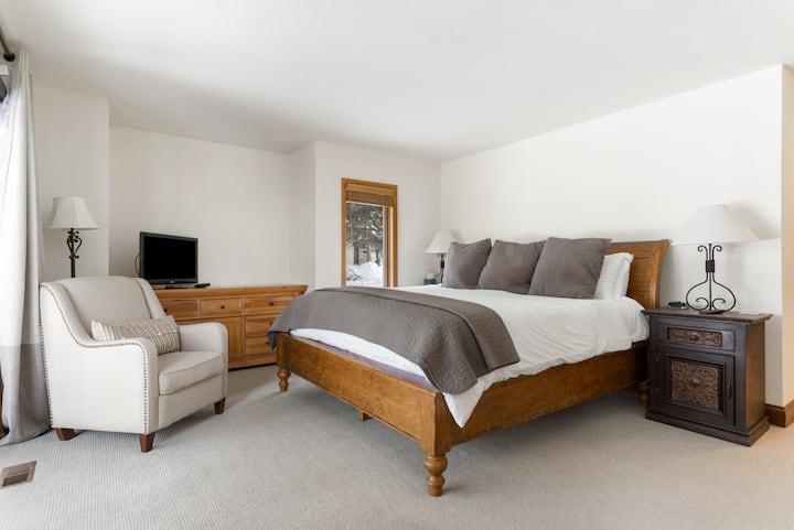 غرفة نوم رئيسية بسرير كينج وتلفزيون وحمام داخل الجناح