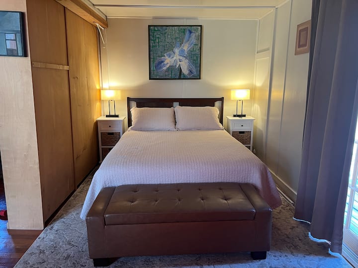 卧室有一扇门通往户外露台，但卧室和客厅之间没有门。 客厅和卧室之间的书架提供了部分隐私。