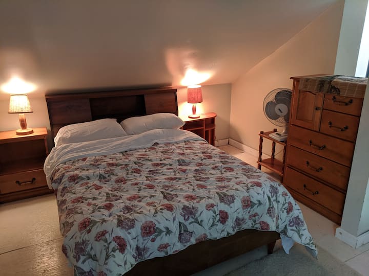 Cama matrimonial de concepto abierto en el segundo piso, con cortinas para la privacidad