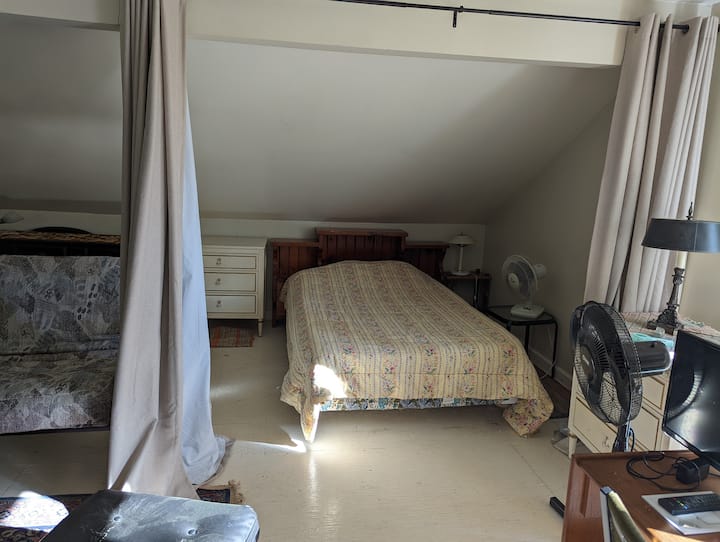 Cama matrimonial de concepto abierto en el segundo piso, con cortinas para la privacidad