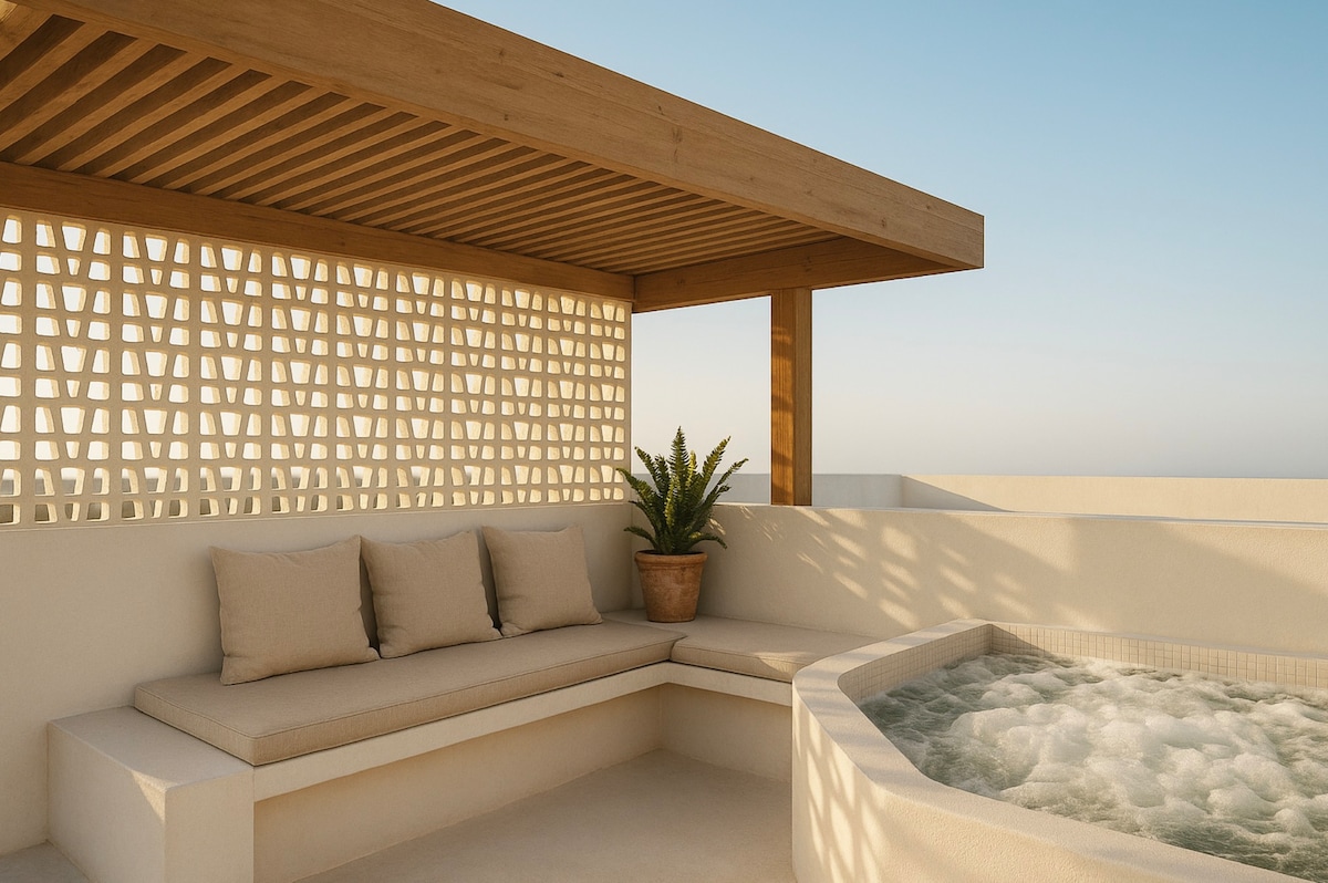 A spacious outdoor area features a comfortable seating arrangement with soft cushions under a wooden pergola. A patio, adorned with a decorative plant, surrounds a private jacuzzi, offering a relaxing environment with scenic views.