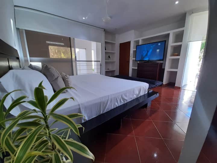 Relaxing king-size bed in the master bedroom, large TV and view of the social area, terrace and pool. 