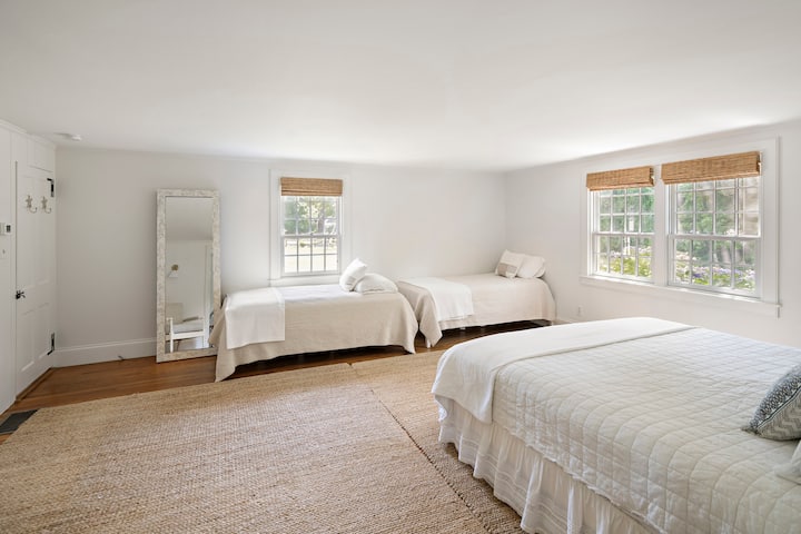 חדר שינה גדול עם מיטת קינג סייז, שתי מיטות נפרדות ומזרנים אמיתיים על הרצפה שמחליקים מתחת למיטות התאומות. 