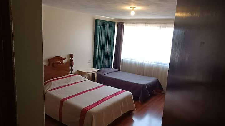 Dhomë e bollshme e vendosur lart, ka një krevat dopio dhe një tek dhe banjën e saj të plotë private